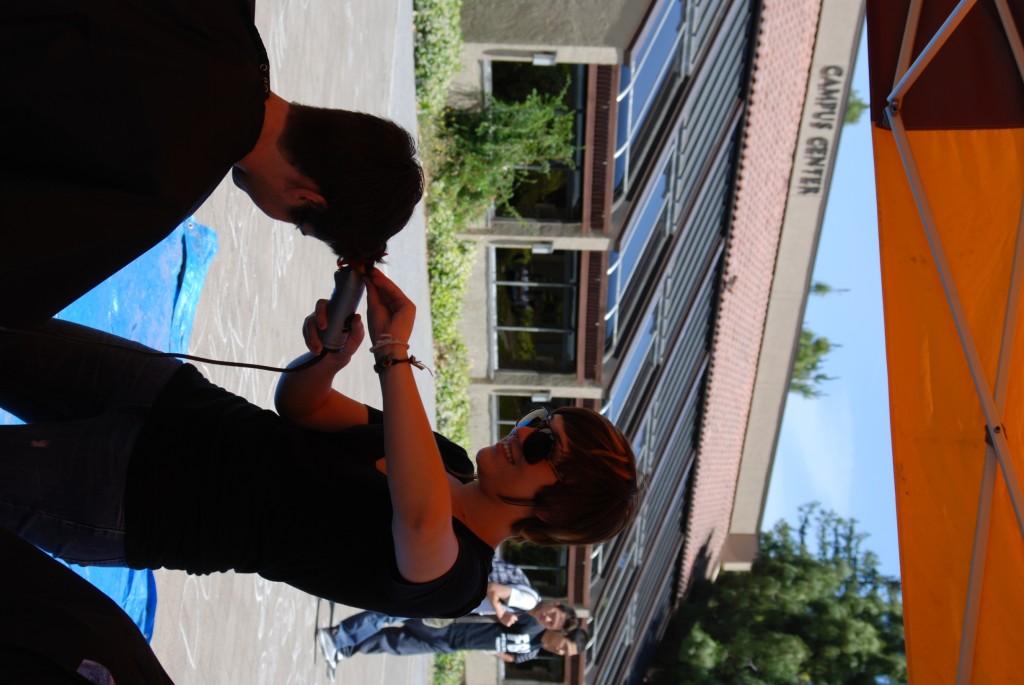 Kelsey Lester-Perry uses her clippers to cut a participant's hair.