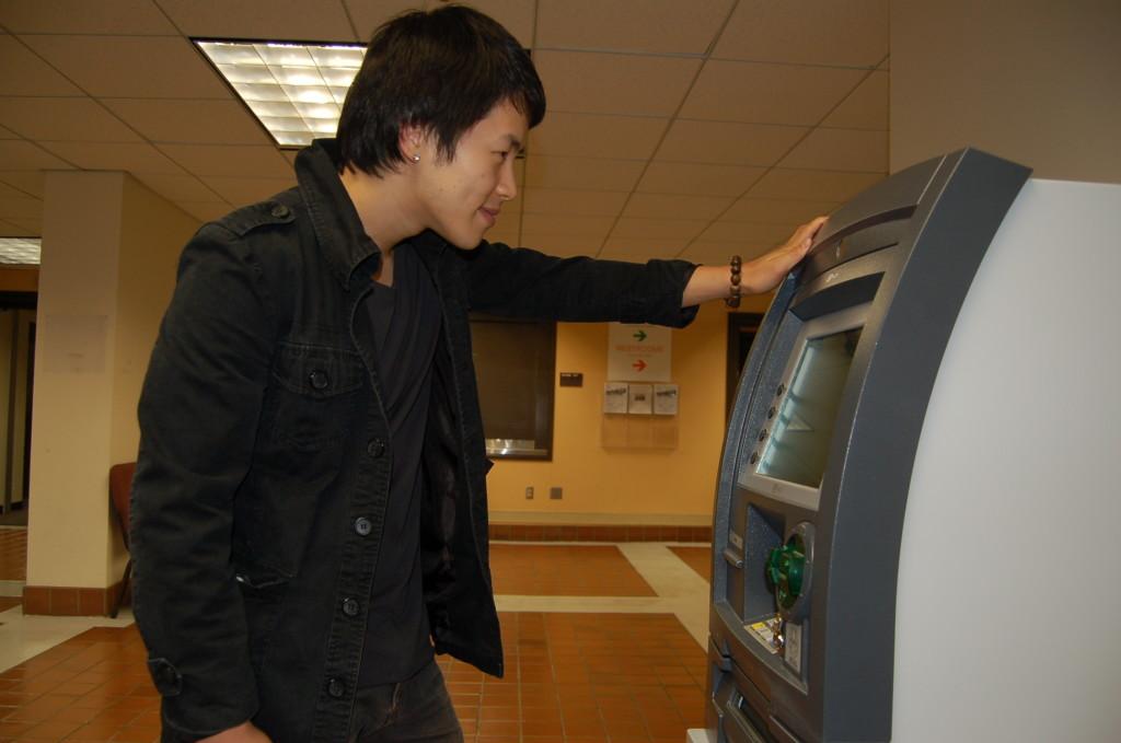 Denny Jeon, 22, business major, at the Higher One automated teller machine outside Le Café in the Hinson Campus Center.