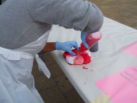 A volunteer tie dyes a pink spiral.