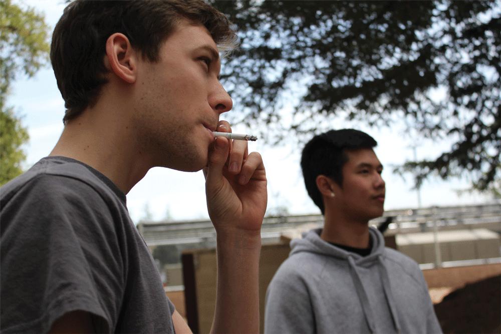 OUTSIDE - Jamie Fernandes [LEFT], undeclared, is among students still not complying to the new policy, standing behind the L4 building near the parking lots to smoke and socialize.