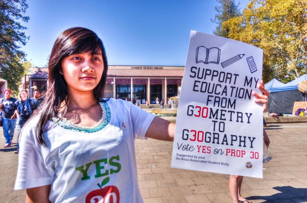 De Anza Student Lynn Hoang shows her support for Prop 30 during a freeze mob on campus