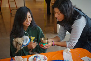 Sharon Chan, 14, and Lydia Sanchez, artist/instructor for the Euphrat Museum, ring the bell in honor of the dead at the Euphrat community art station.
