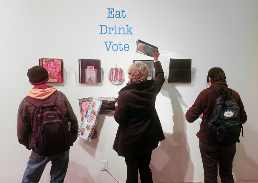 Guests inspect work created by professor Eugene Rodriguez’s photography students, entitled “Eat Drink Vote Love.”