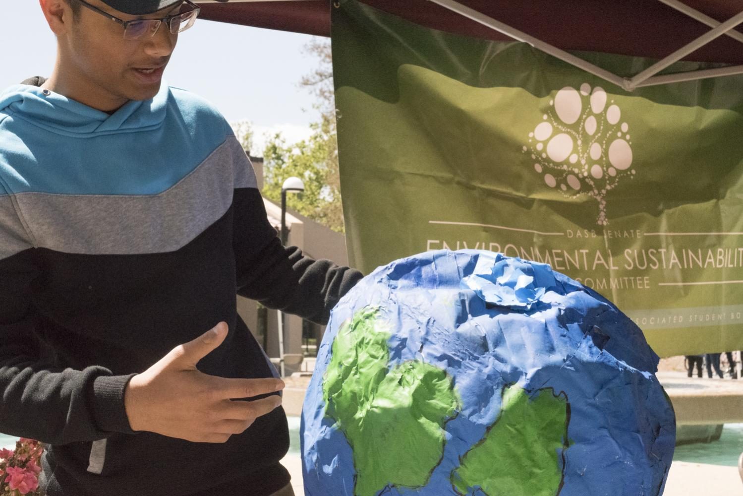 Adita Vishwakarma, 18, engineering major, explains the importance of environmental sustainability on a paper-mache globe made out of old La Voz issues