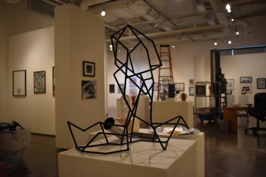 Art pieces stand scattered apart from each other as the lightening for the exhibit is set up. 