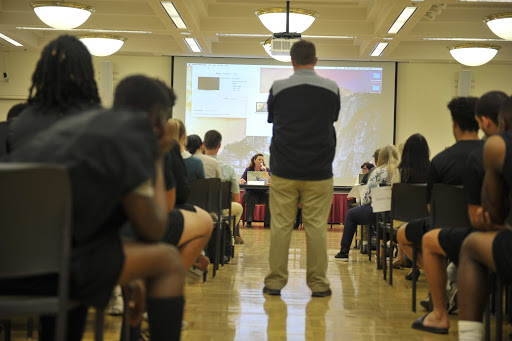 Football head coach Tony Santos stands in the middle aisle of the present onlookers with a majority of De Anza’s Football team present in the hearing of Football’s call to elimination.