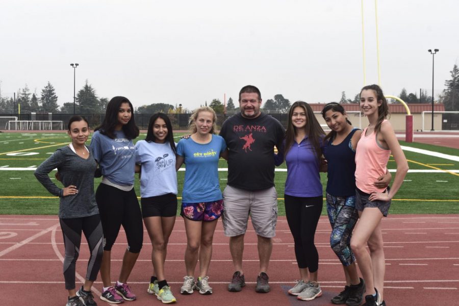 The womens cross country team poses together with their coach.