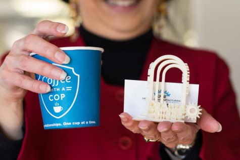 Foothill-De Anza Chancellor Judy Miner holds up a cup of coffee and a 3D printed De Anza College logo.