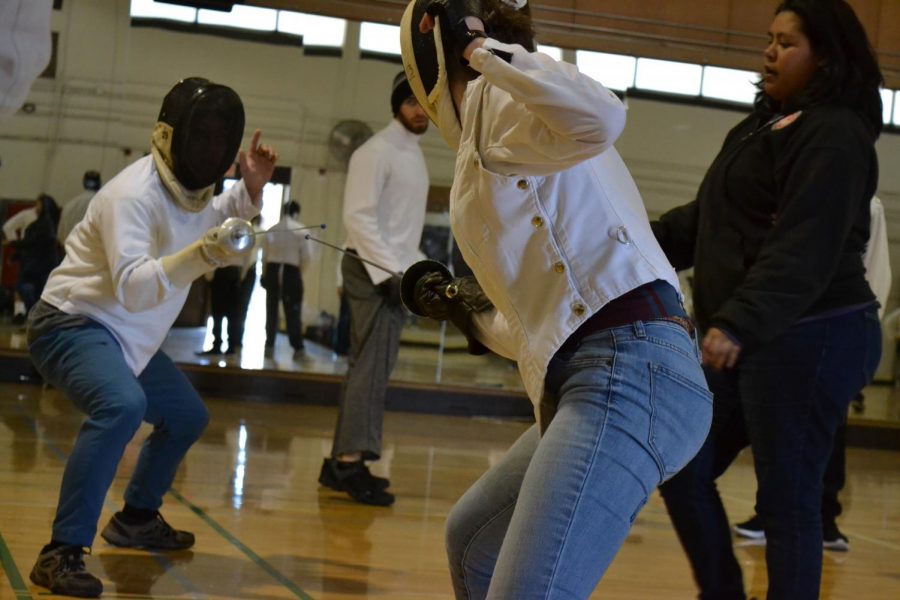 Two masked students face off in a friendly spar during fencing class on March 11.