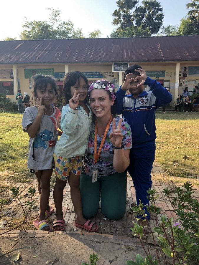 De Anza nursing graduate Emily Miller makes a peace sign and poses with kids. 

Source: Emily Miller