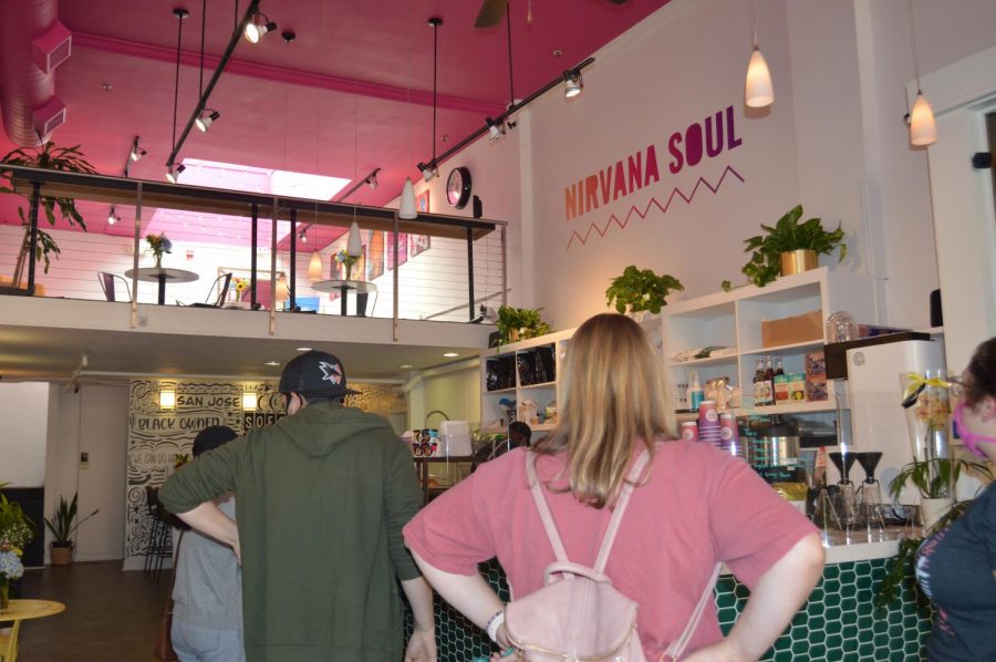 Customers lined up behind a counter with the words Nirvana Soul on the wall.
