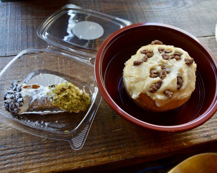 (Left) Cannoli coated with chocolate chips and pistachio flakes and covered with powdered sugar. (Right) A cinnamon bun topped off with walnuts.