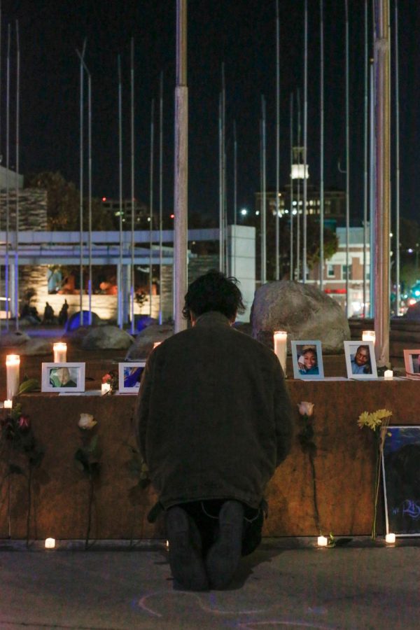 A participant kneels in front of the pictures of transgender victims and prays.