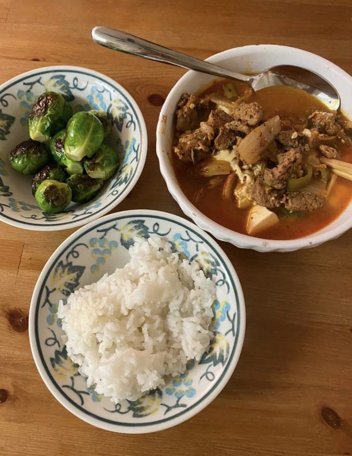 Kimchi soup, a Korean stew-like dish, partnered with a bowl of steamed rice and brussell sprouts.