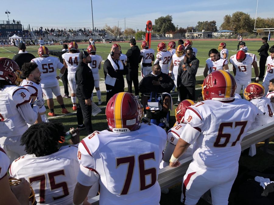 Coach Tony Santos (center, white towel) and his staff address their football team ahead of their final game together against Yuba College on Nov. 8. 