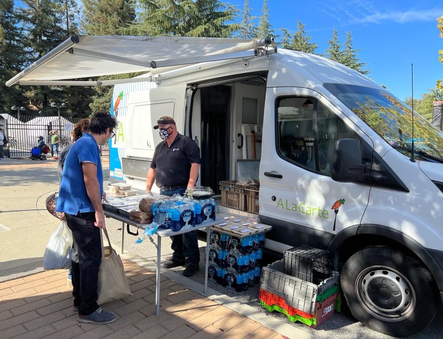 A La Carte staff of Leaves & Fishes Family Kitchen hands out prepared food to those in line at De Anza Colleges Parking Lot A on Oct. 25 . 