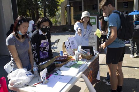 Art Guild of De Anza officers stand at their table, showing their artwork to interested students in the Main Quad on Oct. 13.