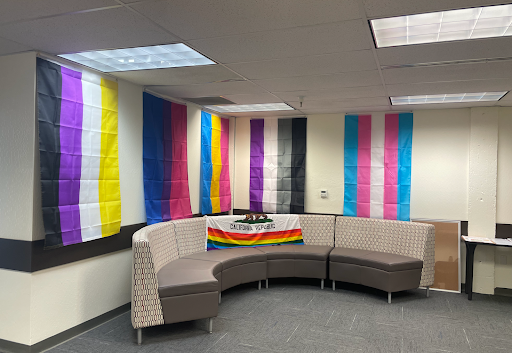 The Pride Center lounge area displays various flags. 