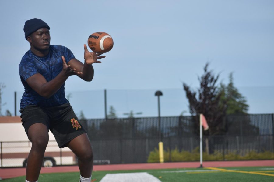 Iretunde Akinsola, 20, a computer science major catches a football during a practice drill at De Anza College.