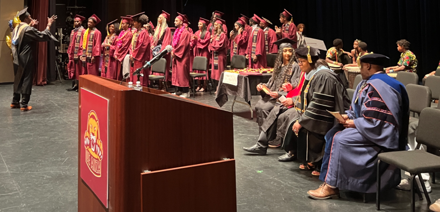 Derrick Felton, psychology instructor, counselor and vice president of the Black Faculty, Staff and Administrators Network, motions for the graduates to be seated at the graduation ceremony on June 16.