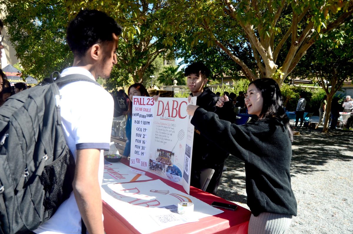 From left, club president Kelly Tran, 18, vice president Scott Nguyen, 17, and ICC representative Renee Ou, 19, present De Anza Badminton Clubs posterboard at the Sunken Garden on Oct. 12.