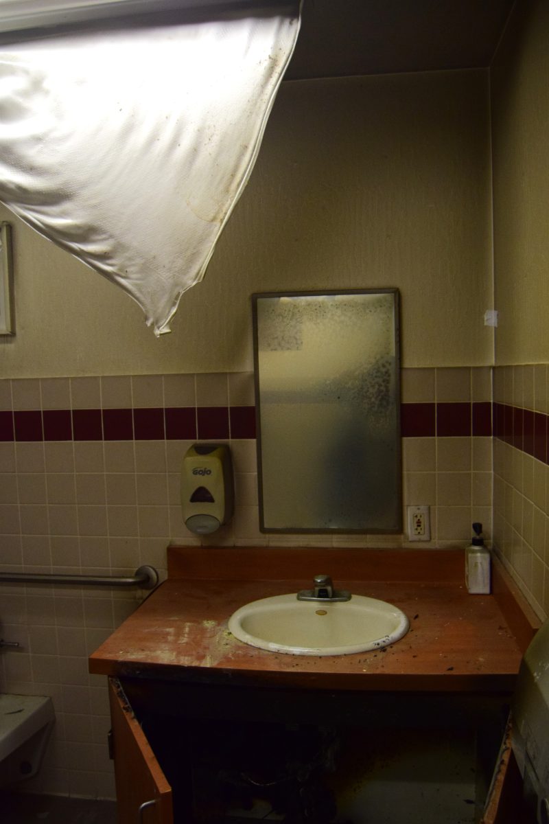 Clouded mirror, melted ceiling light cover and burn damages caused by a fire in a gender-neutral staff bathroom in the L-wing.