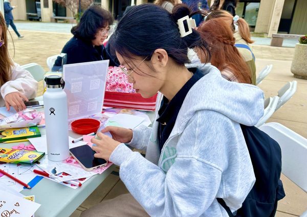 Tram Nguyen, 21, business major, making a letter for a loved one in the main quad on De Anza Campus.