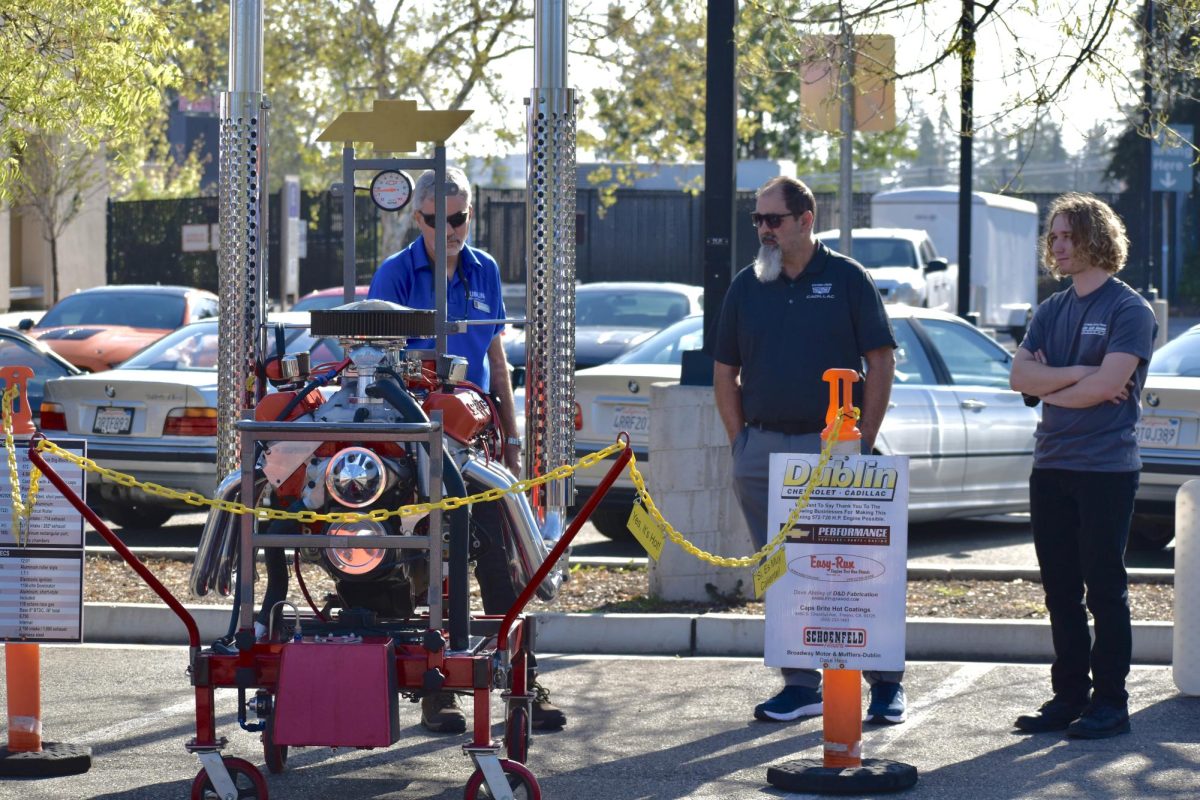 (from left) Jack Sandi, wholesale manager, J.J. Vandongen, service manager and Brendon Pearson, 21, automotive technology major, display a Chevy Tall-Deck Big-Block V-8 engine. Designed for drag racing, the engine was deafening from any location when it was periodically turned on. 