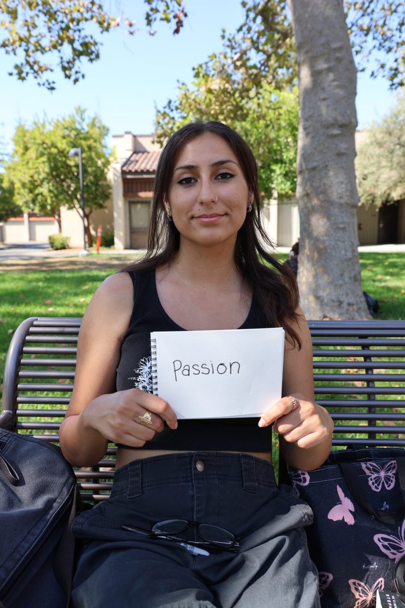 Meli Rodriguez, 18, a business administration major, sits on the bench and holds her favorite word, "passion," near the S quad on Oct.3.