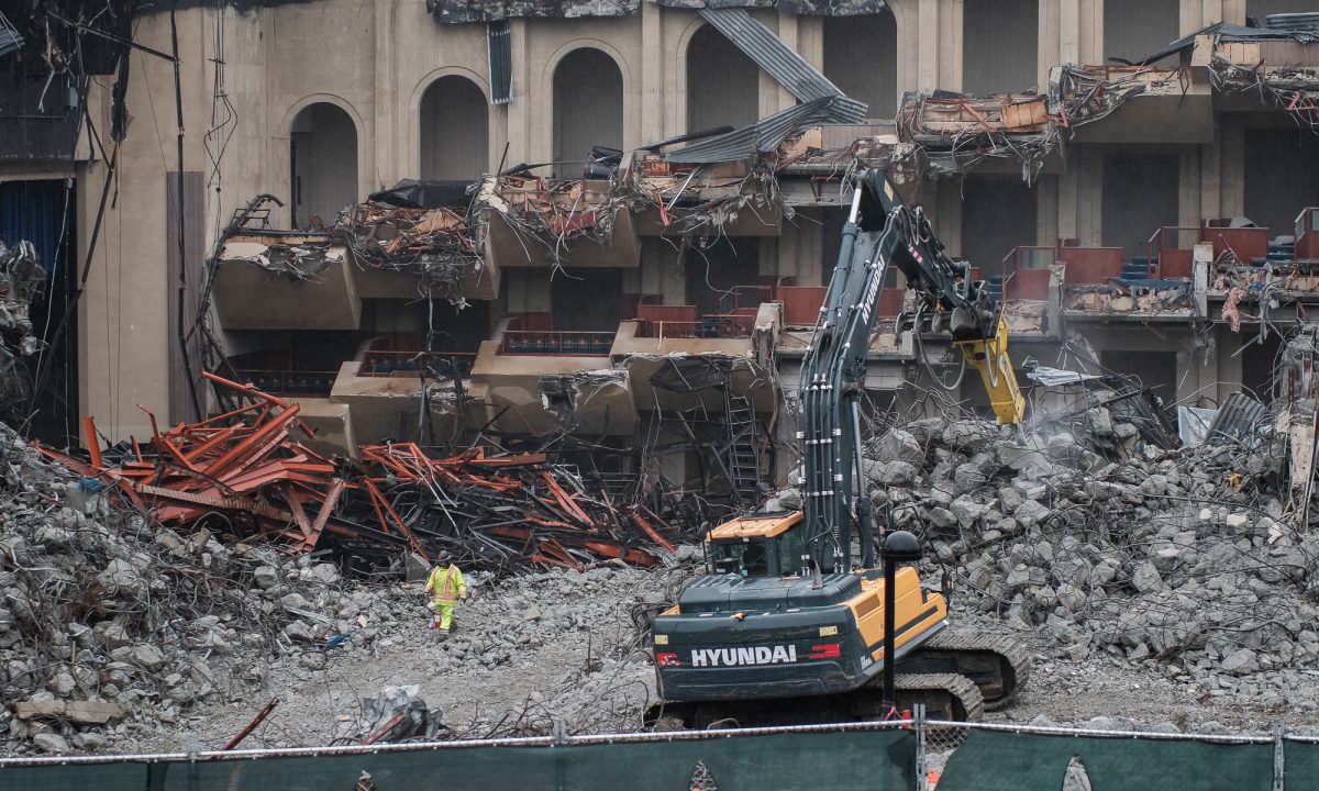 An excavator breaks down chunks of concrete while a worker walks through the rubble that now fills the former interior of the Flint Center on Nov. 25.