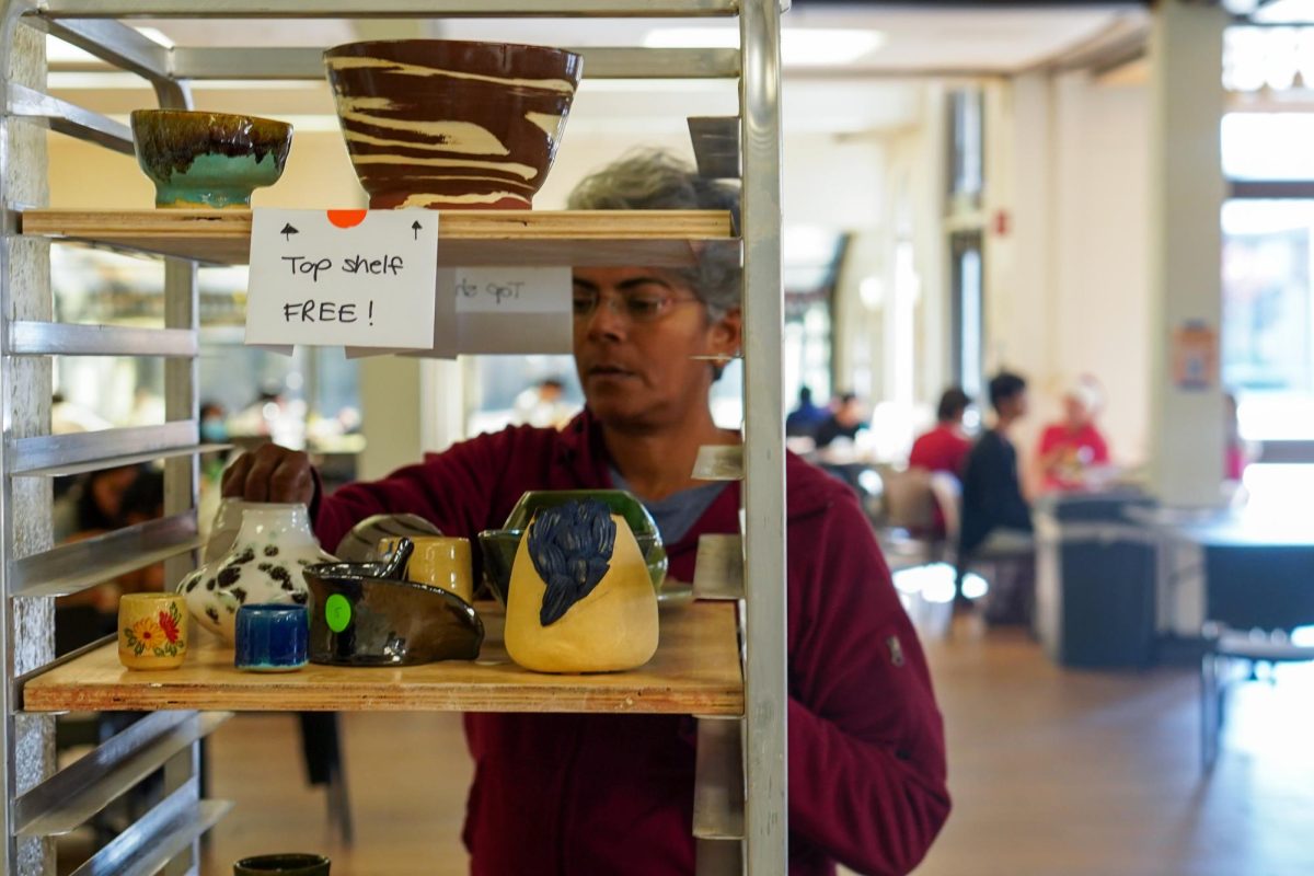 Bala Subramanian, 57, ceramics major, adjusts the pottery on the $10 and under rack and the pottery sale in the Hinson Campus Center on Nov. 2.