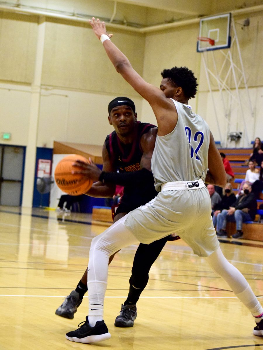 Guard James Thomas (De Anza No. 12), 22, sociology major, takes the ball around wing Keshawn Johnson (San Mateo No. 32) in the College of San Mateo gymnasium on Jan. 15.