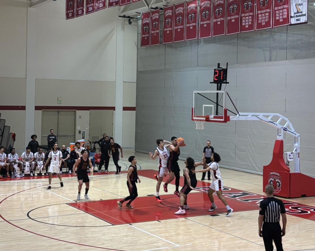 Sean Crowley (No. 32), 20, business administration major, rushes at the hoop from the paint as the Mountain Lions and San Francisco Rams watch in the City College of San Francisco main gymnasium on Feb. 14.