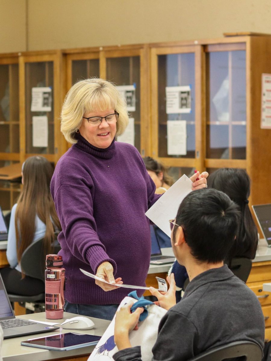 Judy Cuff-Alvarado, biology instructor, gives a paper to a student in her Introductory Biology class in S52 on Jan. 30.