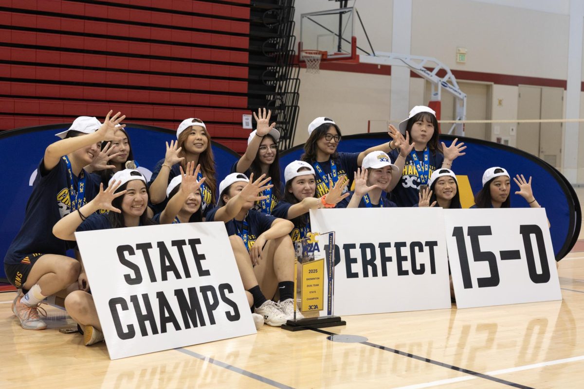 The De Anza College women’s badminton team poses with its 3C2A badminton championship trophy at the City College of San Francisco on May 8. The team members flash five fingers to represent their fifth state championship under head coach Mark Landefeld. The team maintained a 15–0 record for the 2025 season, including the championship match.