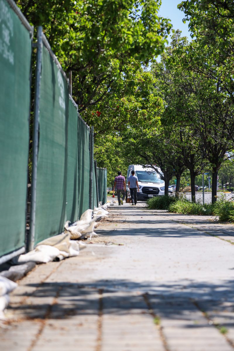 Two people walk past the fences surrounding the Whole Foods Market on Stevens Creek Boulevard following its closure because of health code violations, May 1.