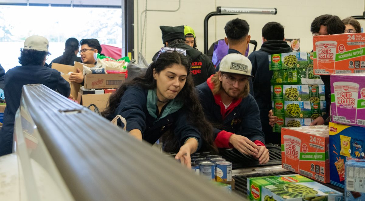 From left, Dani Falmoe, 22, and Graham Lee, 20, both automotive technology majors, load food into the back of a pickup truck for delivery to The Hub during the Auto Tech canned food drive on Nov. 25.