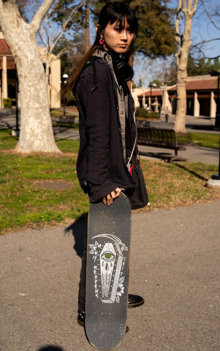 Koi Nguyen, 20, sociology major, skates to school on a decorated skateboard, with a soda cap adding an innovative detail to their style.