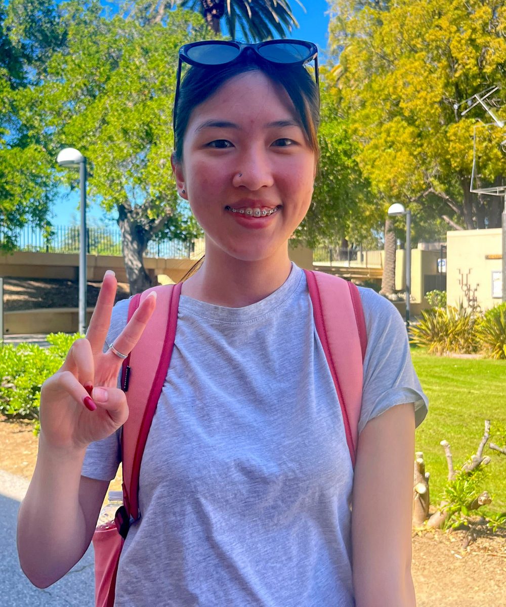 Iris Wei, 18, biology major, holds up a peace sign outside the A quad, standing near the Baldwin Winery building on March 17.