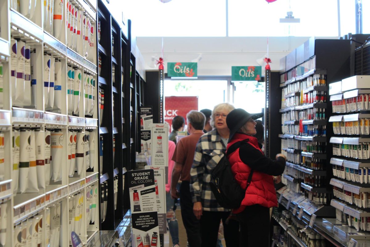 Two customers talk and laugh at the front of the store as they search for canvases and paints. 