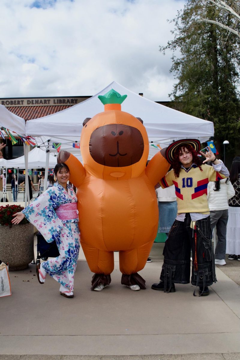 From left, Isa Ono, 22, psychology major, Mason Li, 19, philosophy major and Henderson Sandoval, 19, psychology major pose together by their club booth in the main quad on March 2.